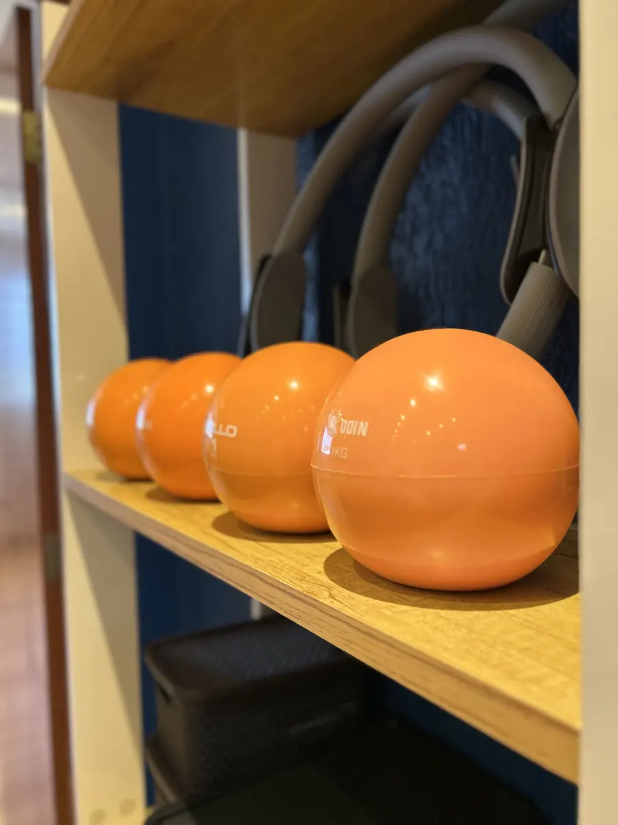 Bolas tonificadoras laranja e anéis de Pilates na estante do studio